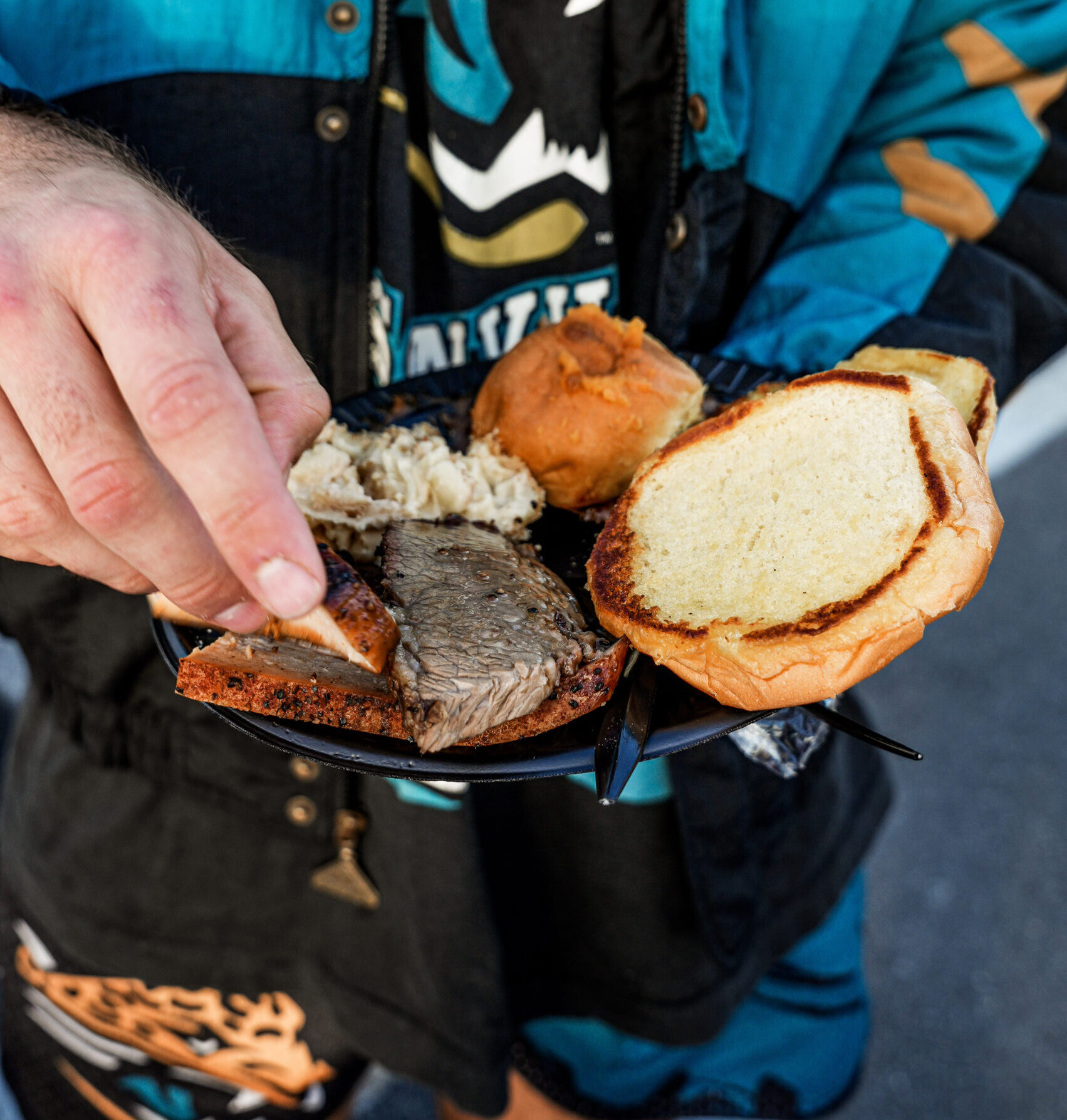 MOJO BBQ catering at a tailgate with someone putting together a slider